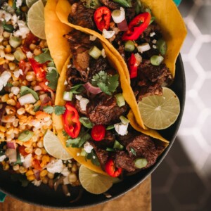 2 fully loaded steak tacos with chopped grilled chuck steak and colorful toppings like peppers, red onion, and cilantro