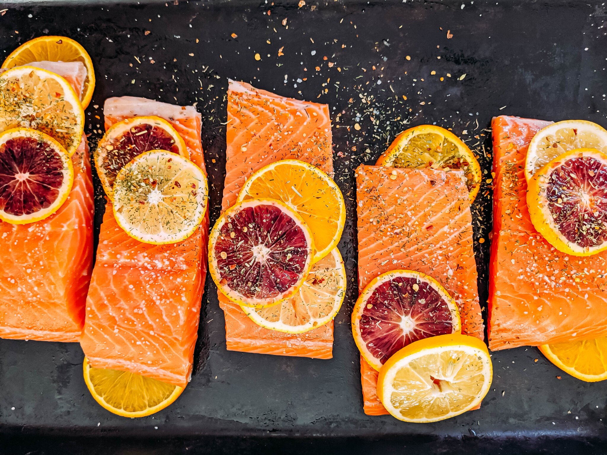 raw salmon on platter with citrus slices and spices sprinkled on top