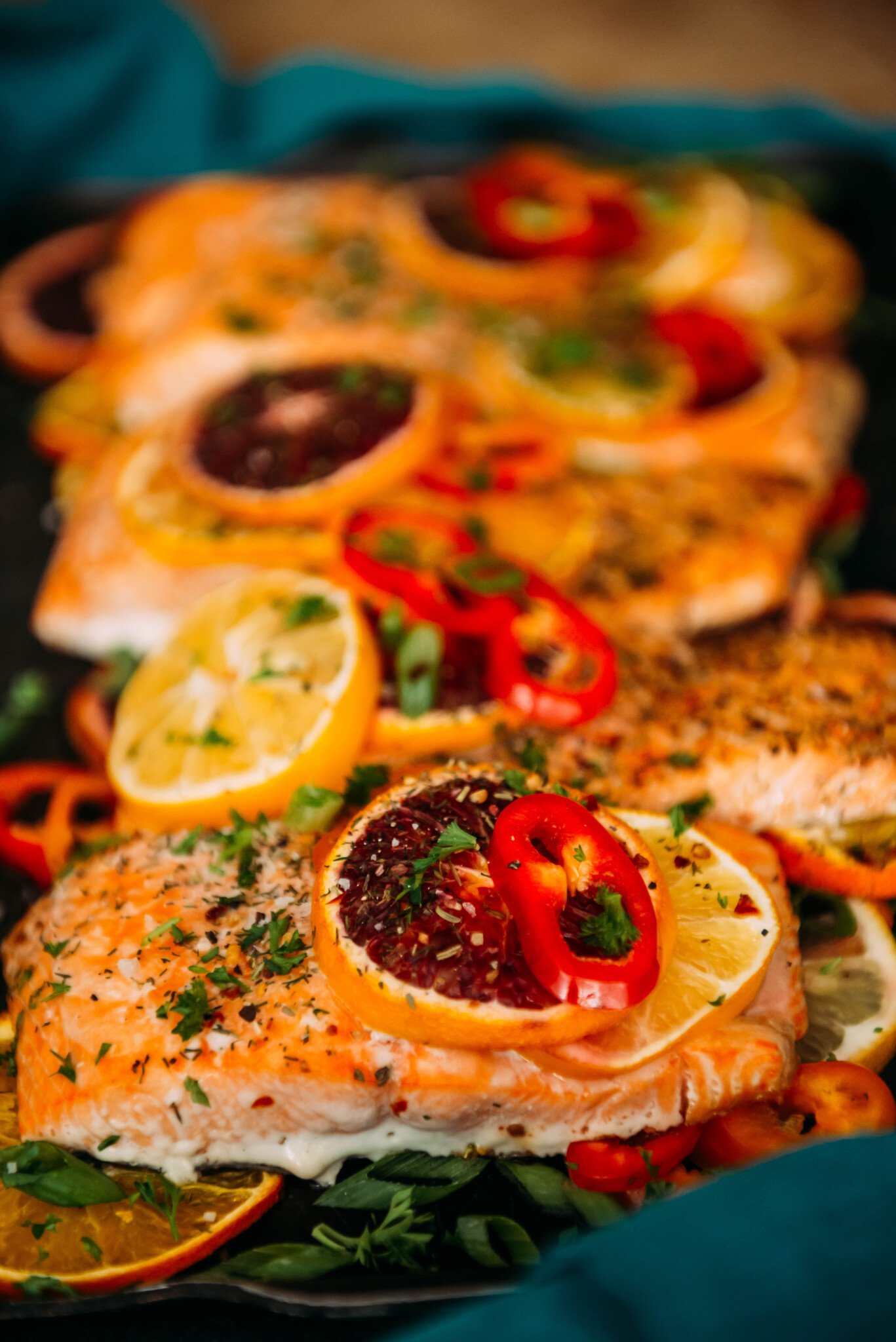 baked salmon topped with bright citrus slices, peppers and herbs