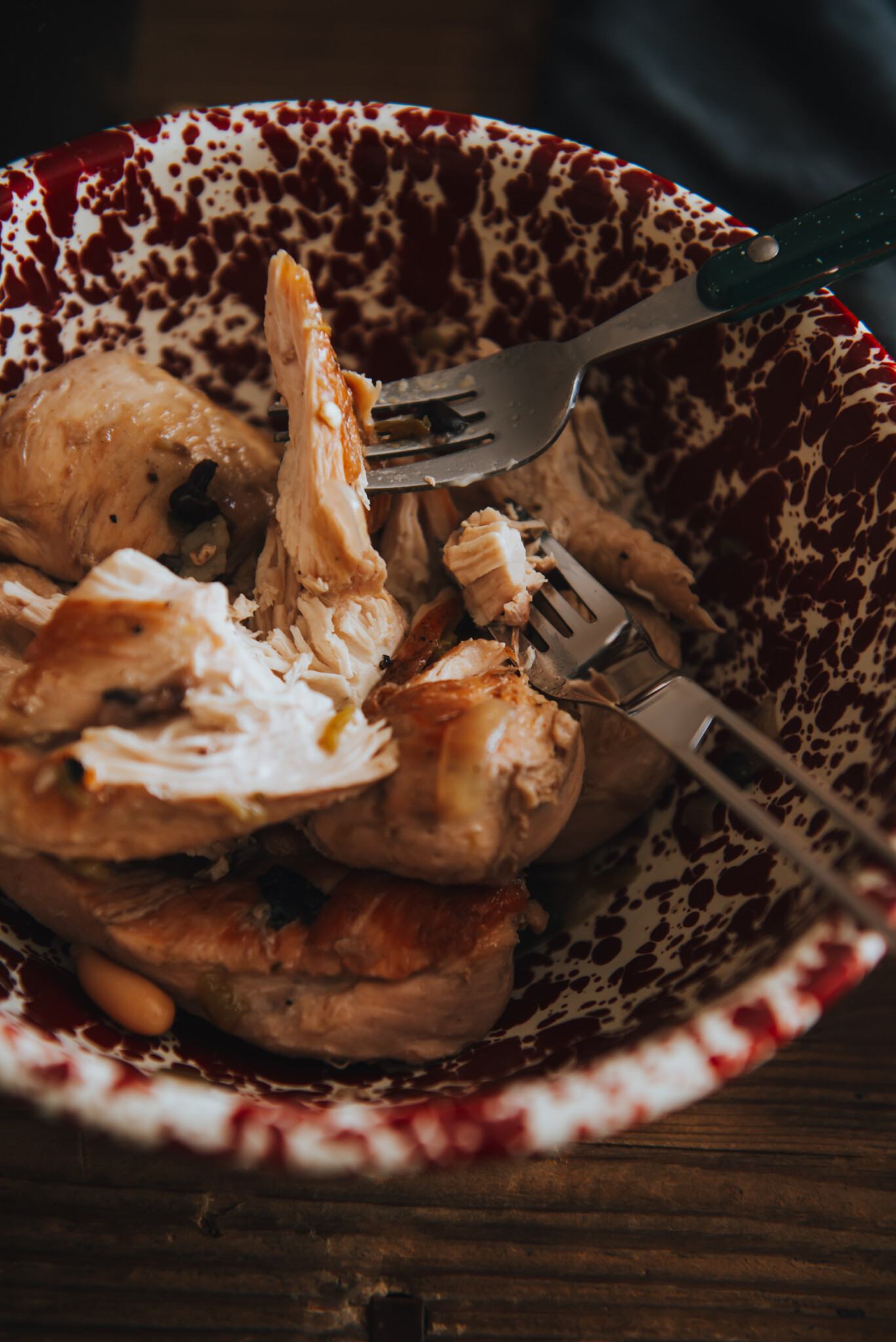 chicken in a bowl being shredded with two forks