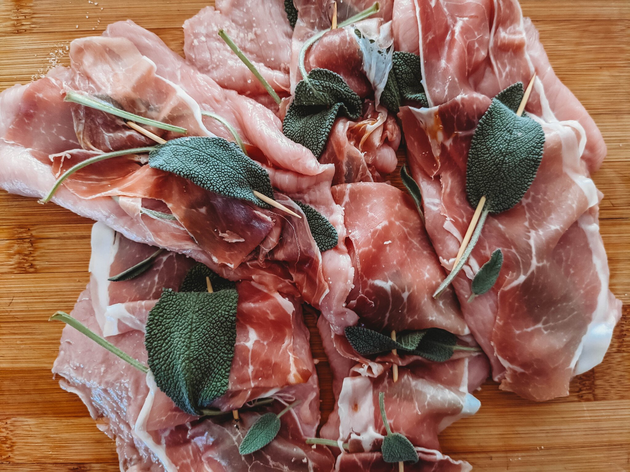 veal prepped for saltimobcca, lined with prosciutto and sage affixed with a toothpicks
