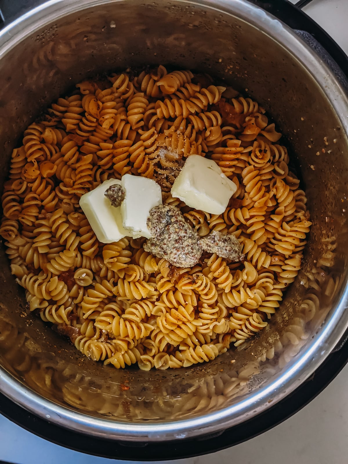 butter, dijon and spices added to cooked pasta to make instant pot mac and cheese.