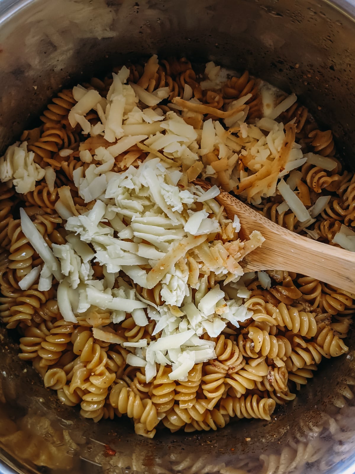 adding cheese to cooked pasta for mac and cheese