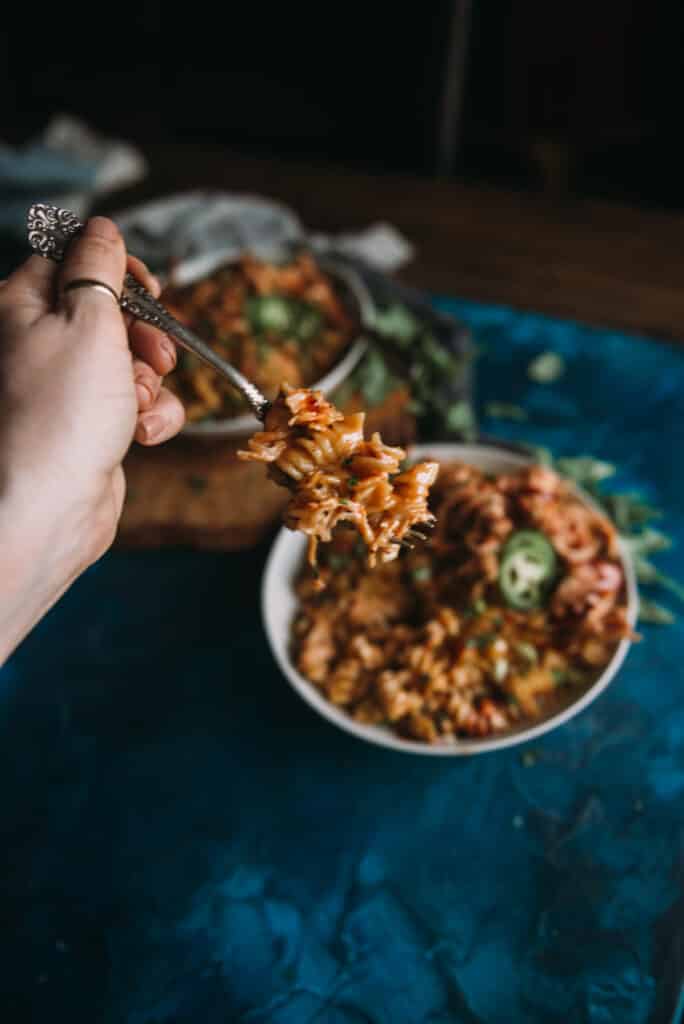hand holding fork with instant pot shredded bbq chicken mac and cheese on it