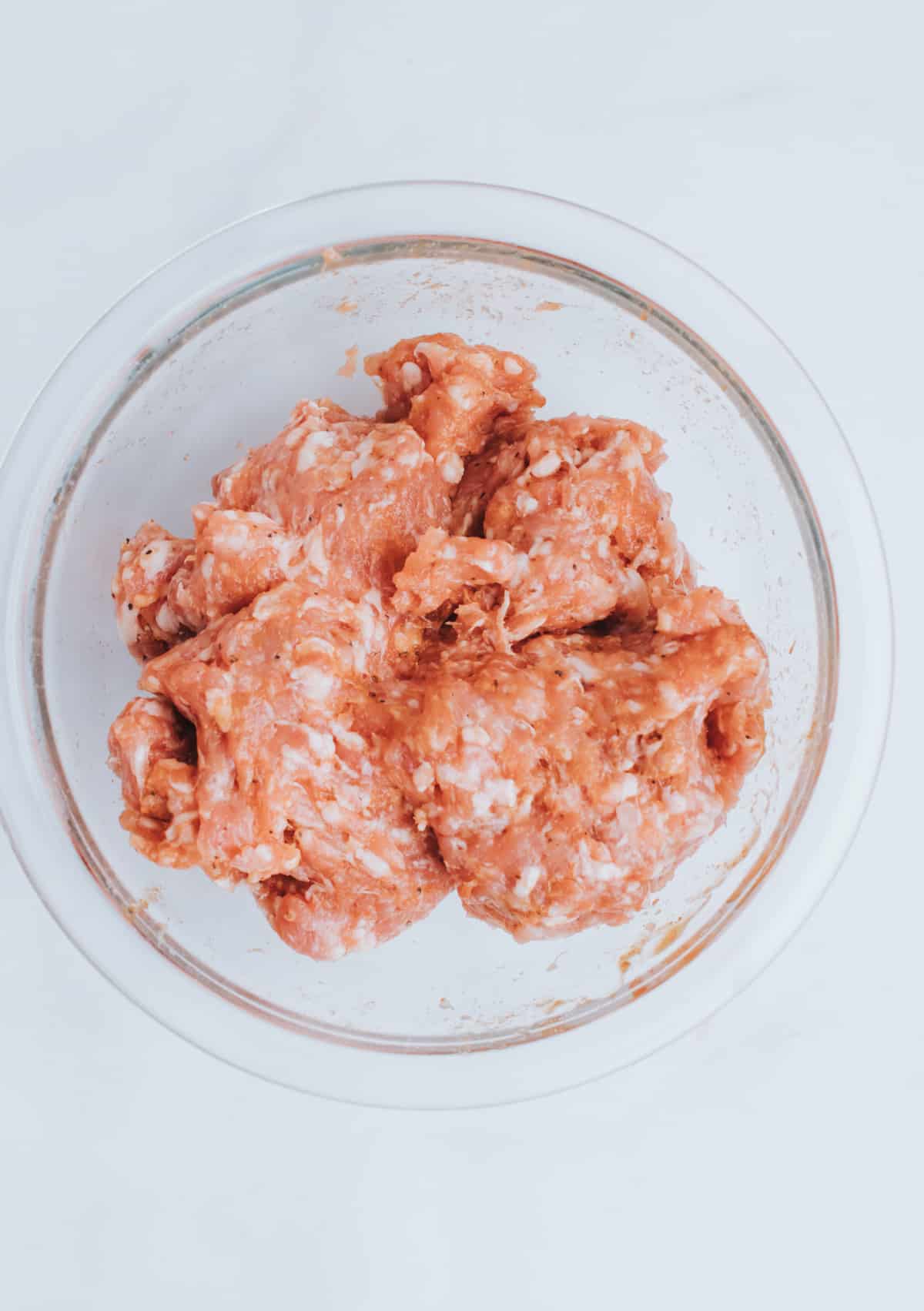 mixing spices to bowl of ground sausage