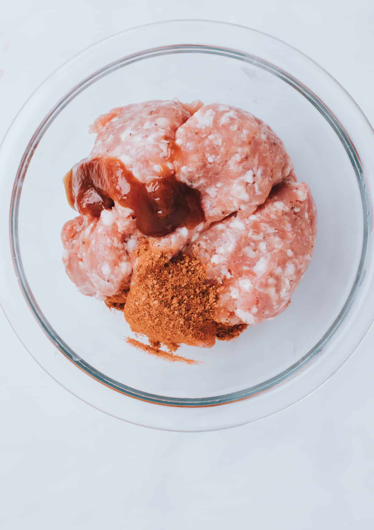 adding spices to bowl of ground sausage