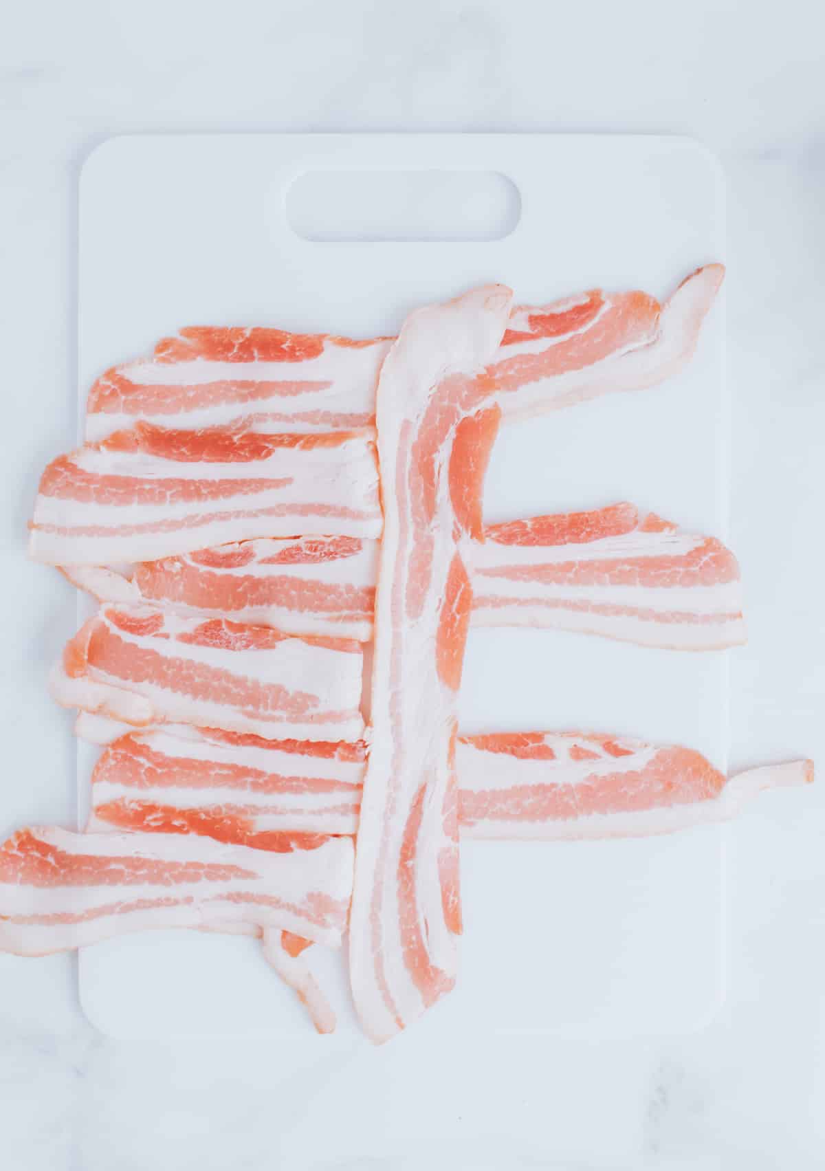 folding strips of bacon on a cutting board