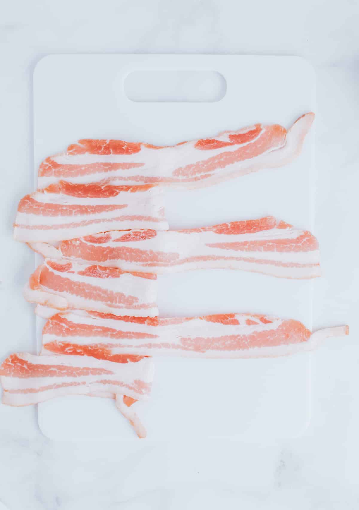 folding strips of bacon on a cutting board