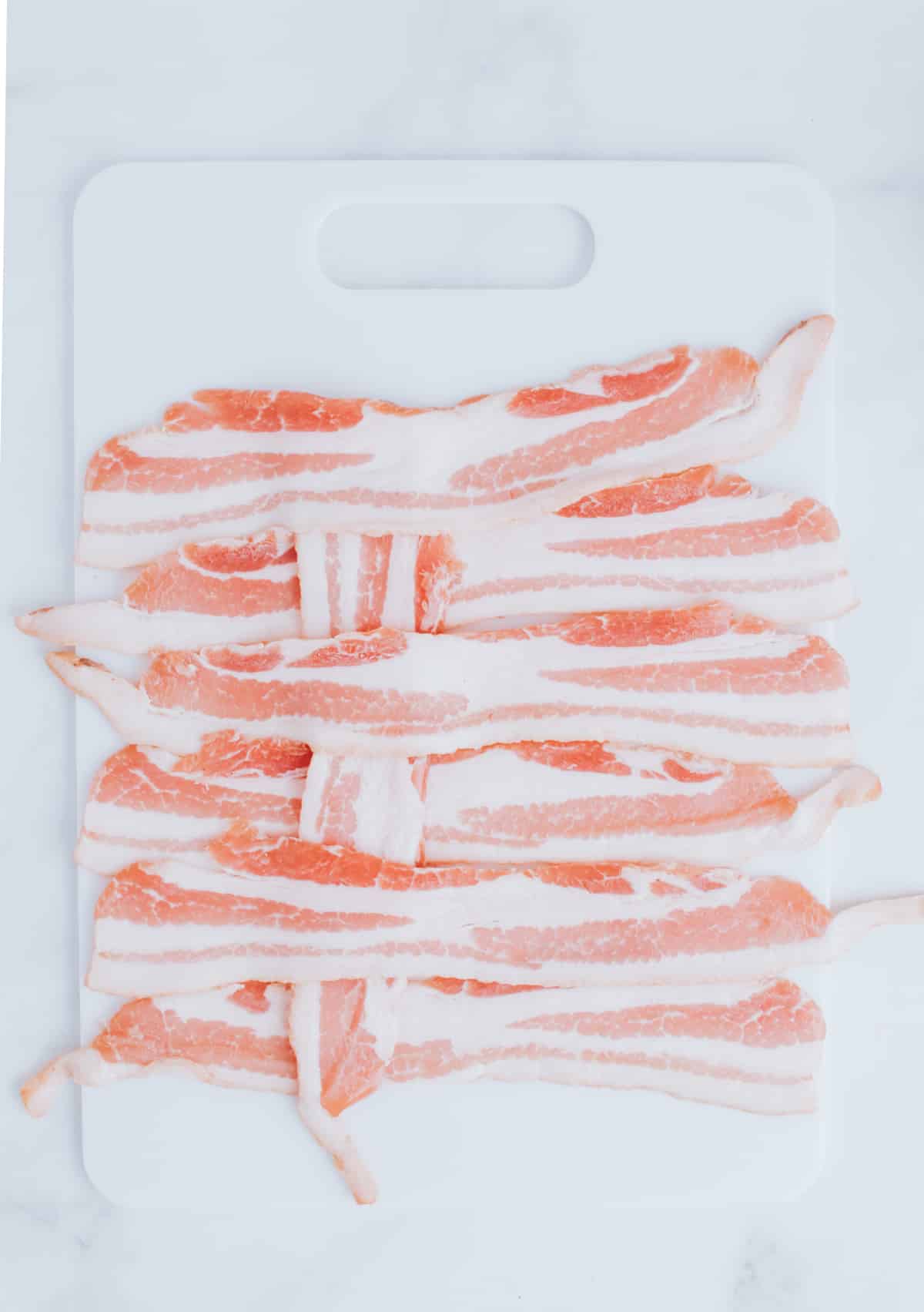 folding strips of bacon on a cutting board