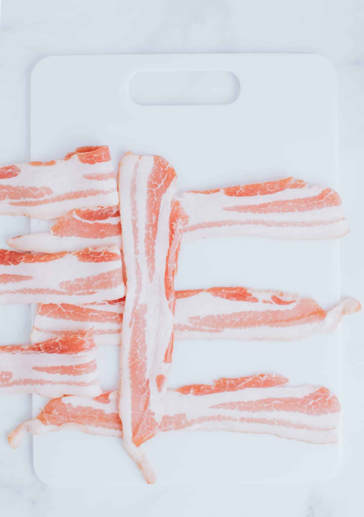 folding strips of bacon on a cutting board