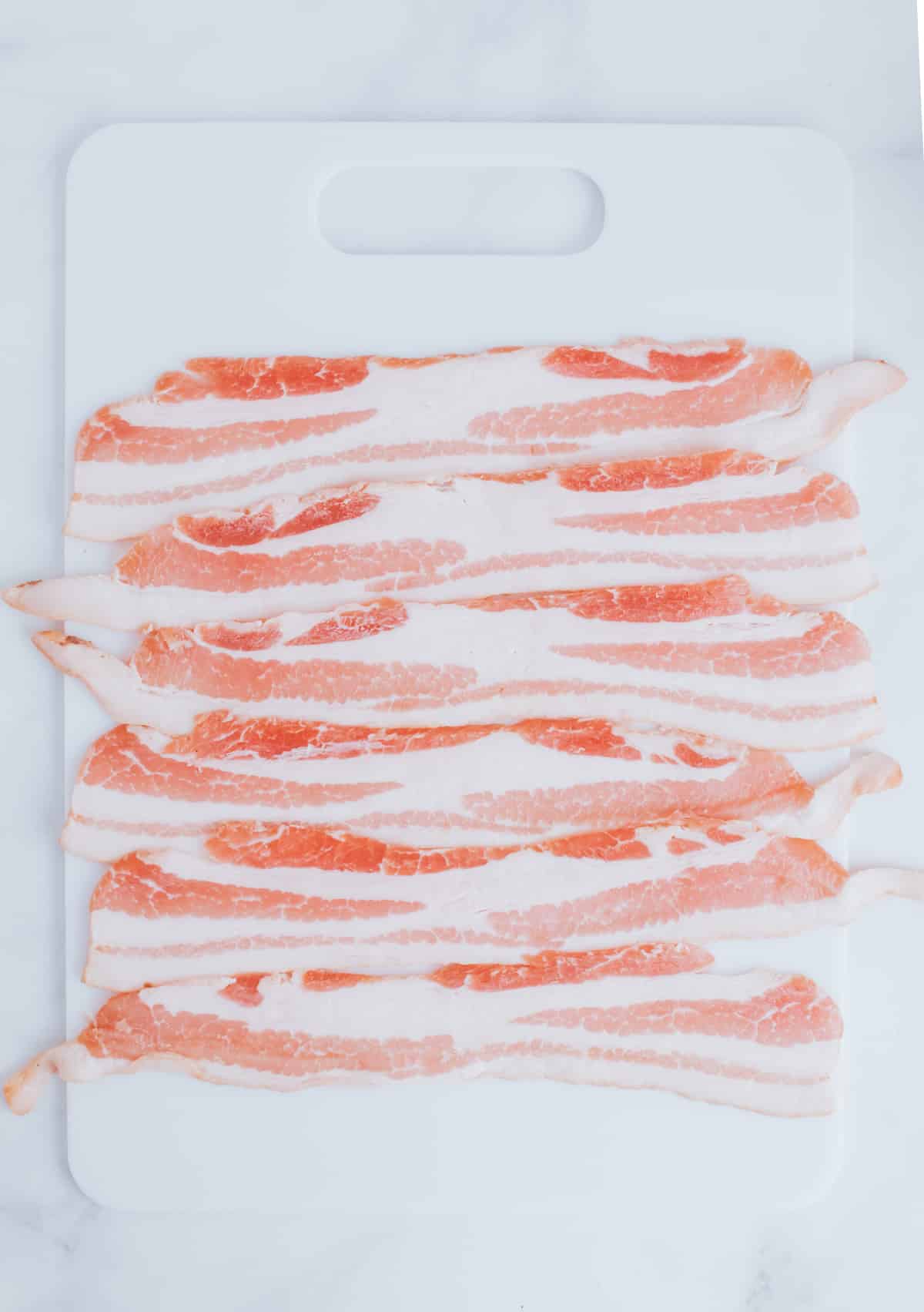 strips of bacon on a cutting board