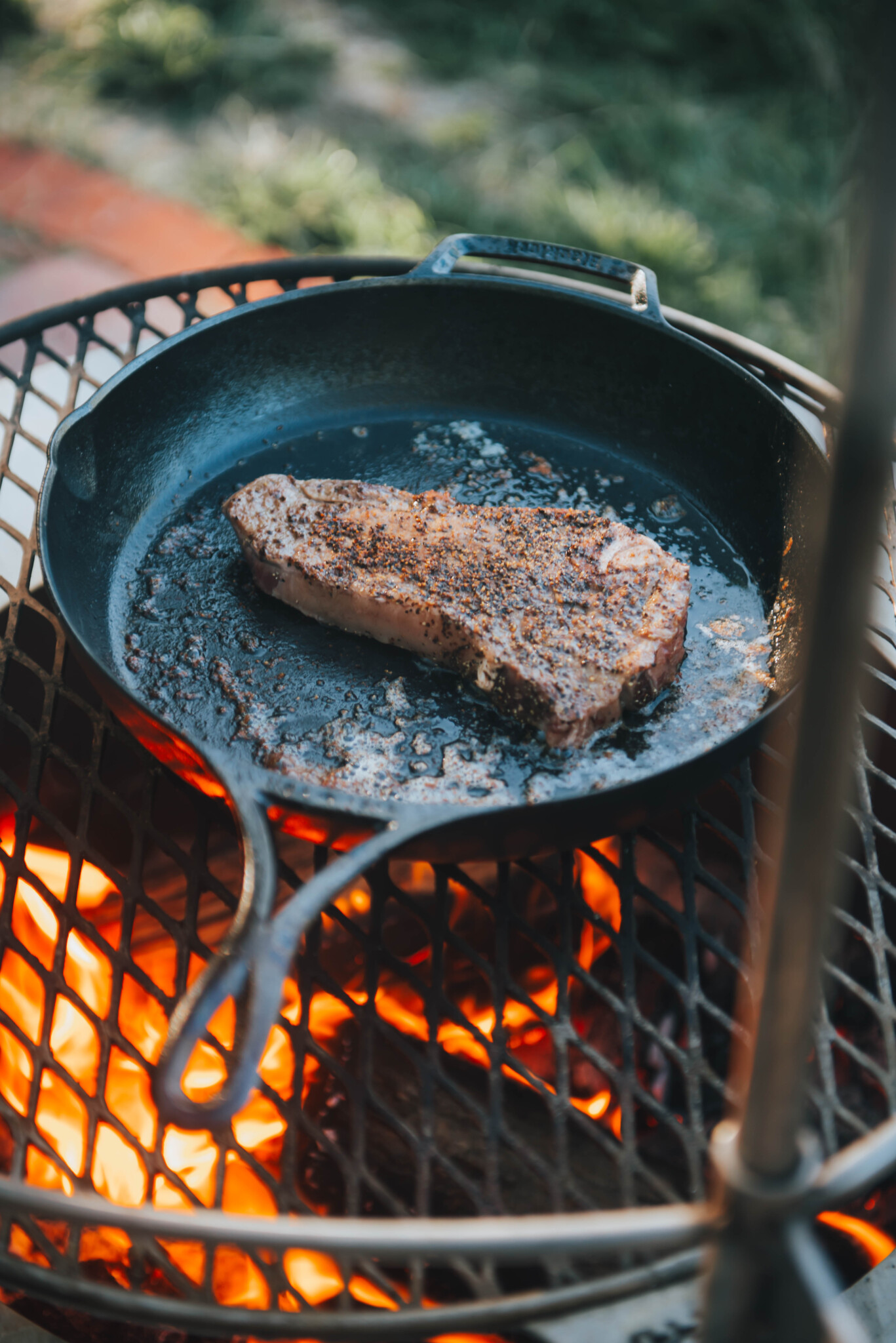 Strip steak in skillet over campfire. 