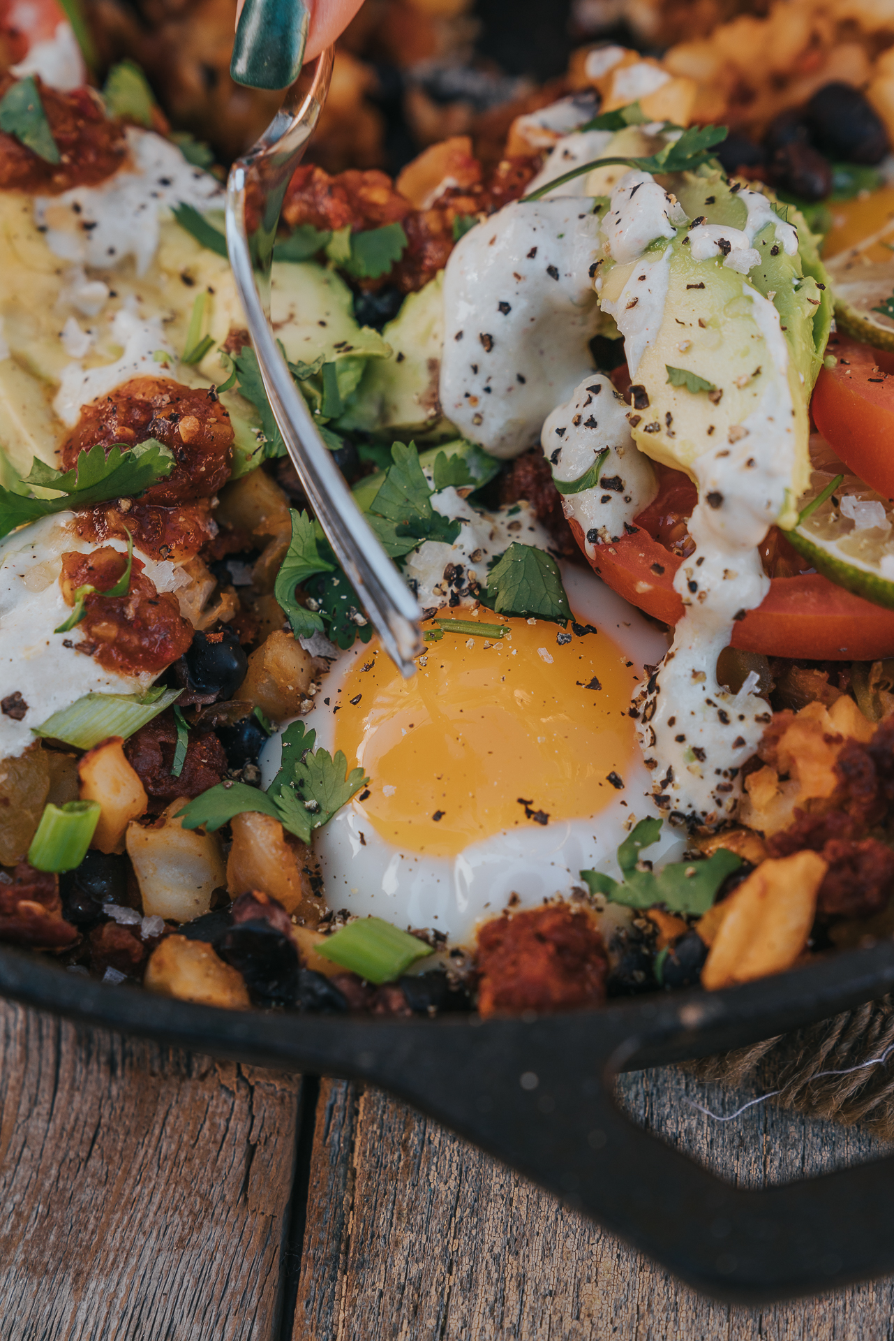 Close up of runny frieg egg in the chorizo, potatoes and toppings. 