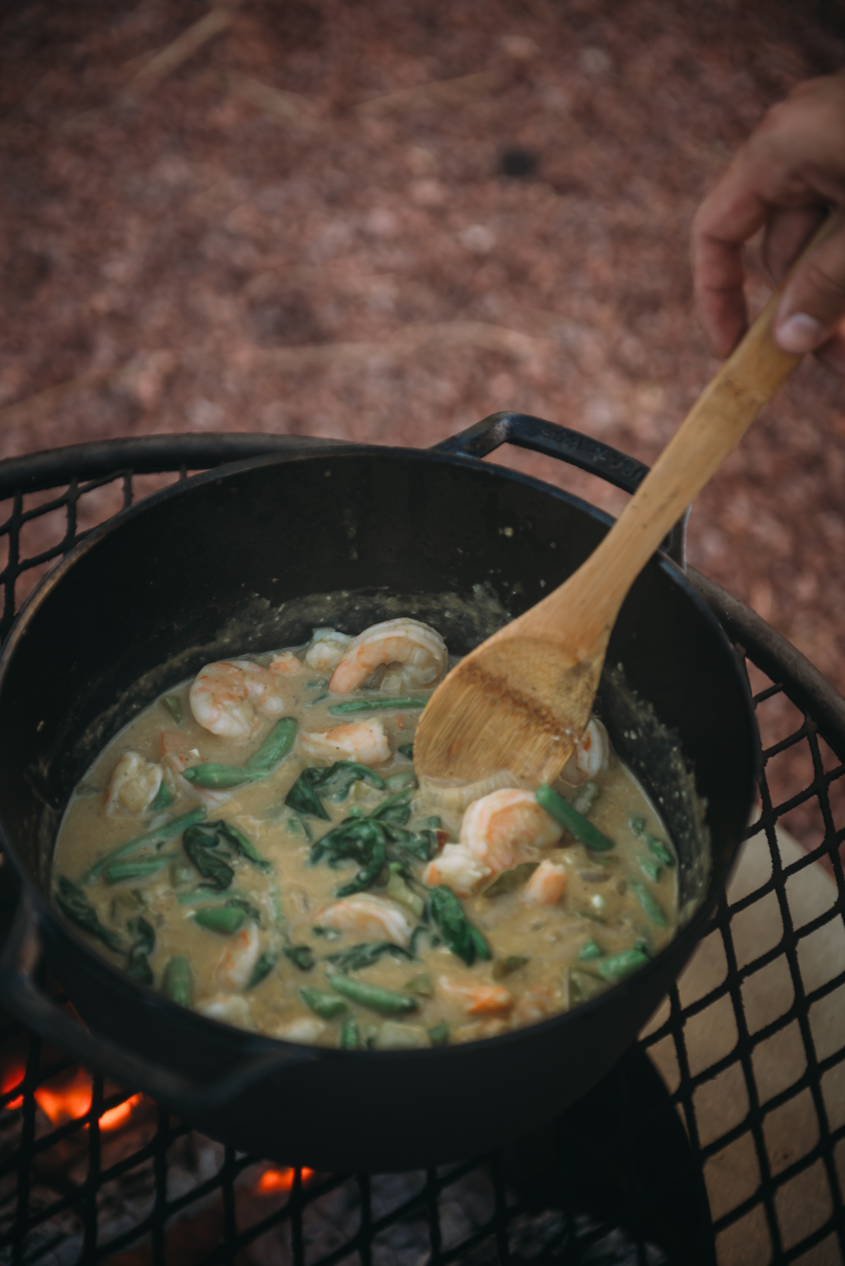 shrimp korma simmering in dutch oven over campfire