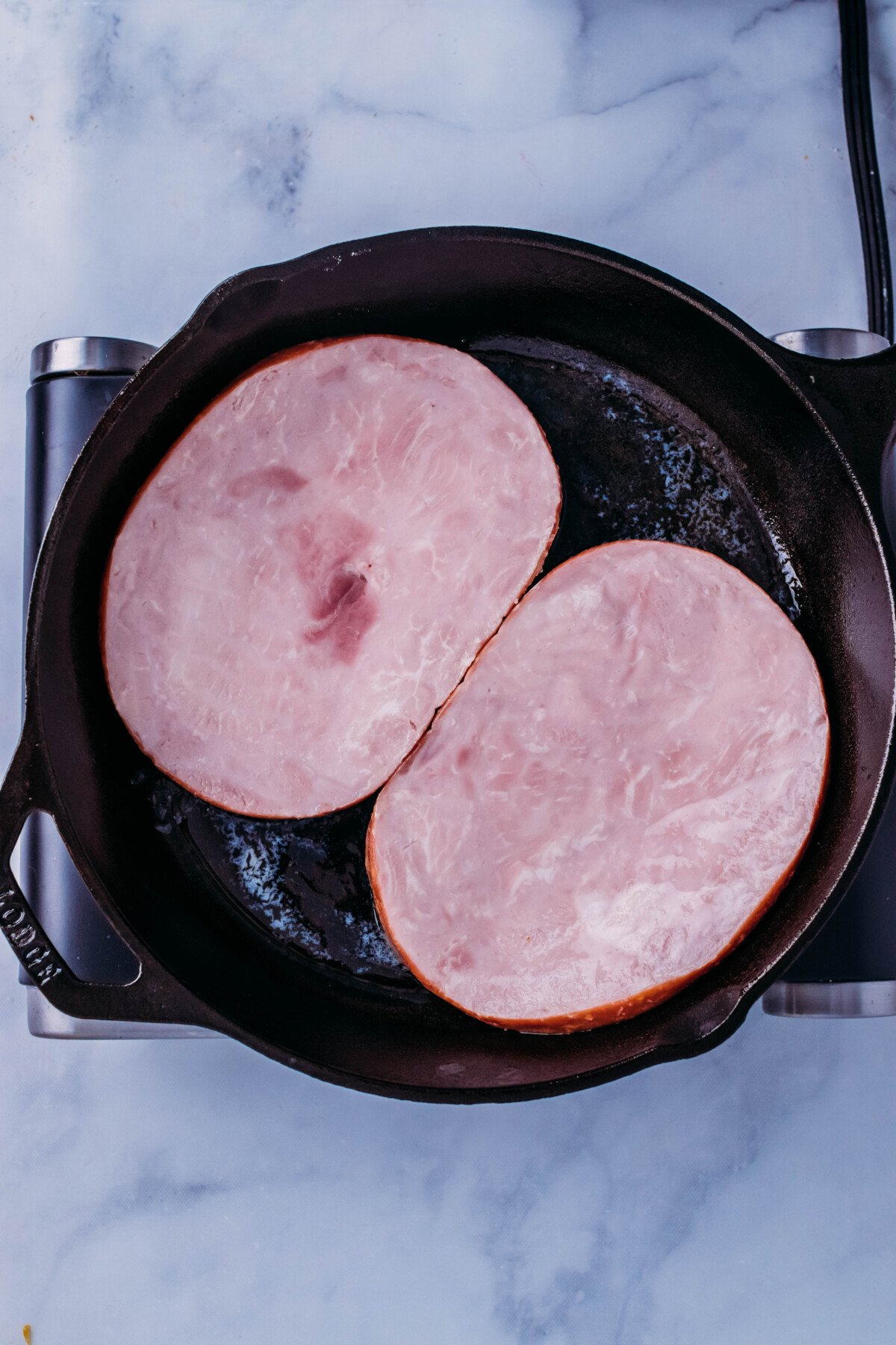 Ham steaks placed in cast iron skillet.