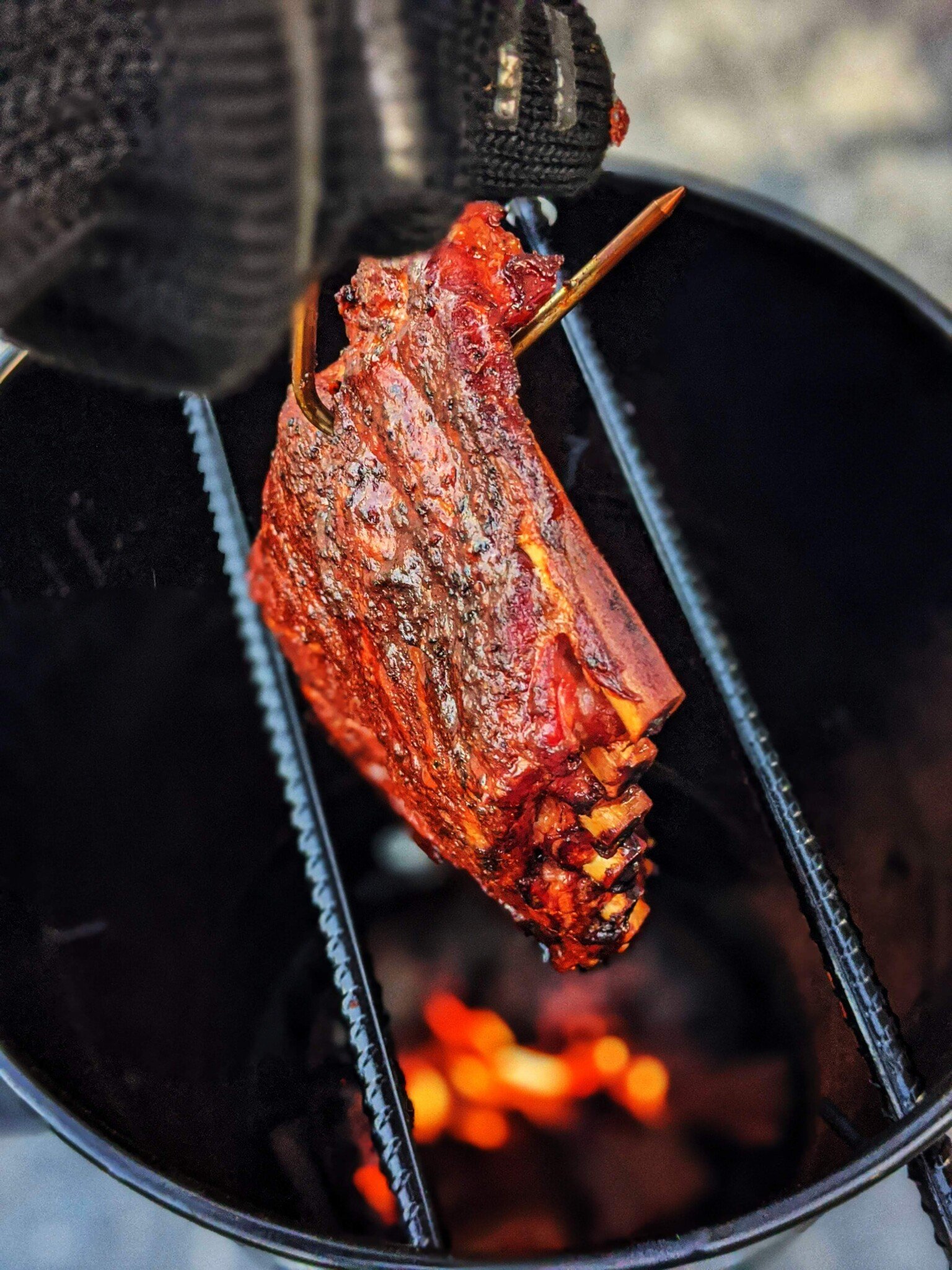 Smoked ribs being pulled from a drum style smoker. 