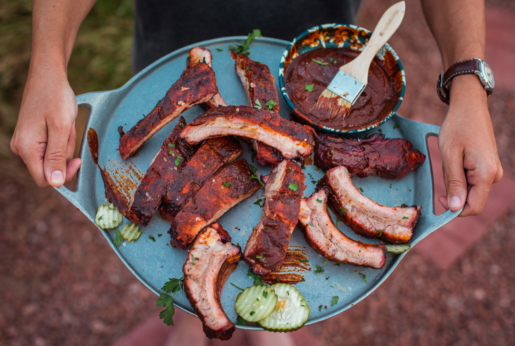 Man holding platters of baby back ribs. 