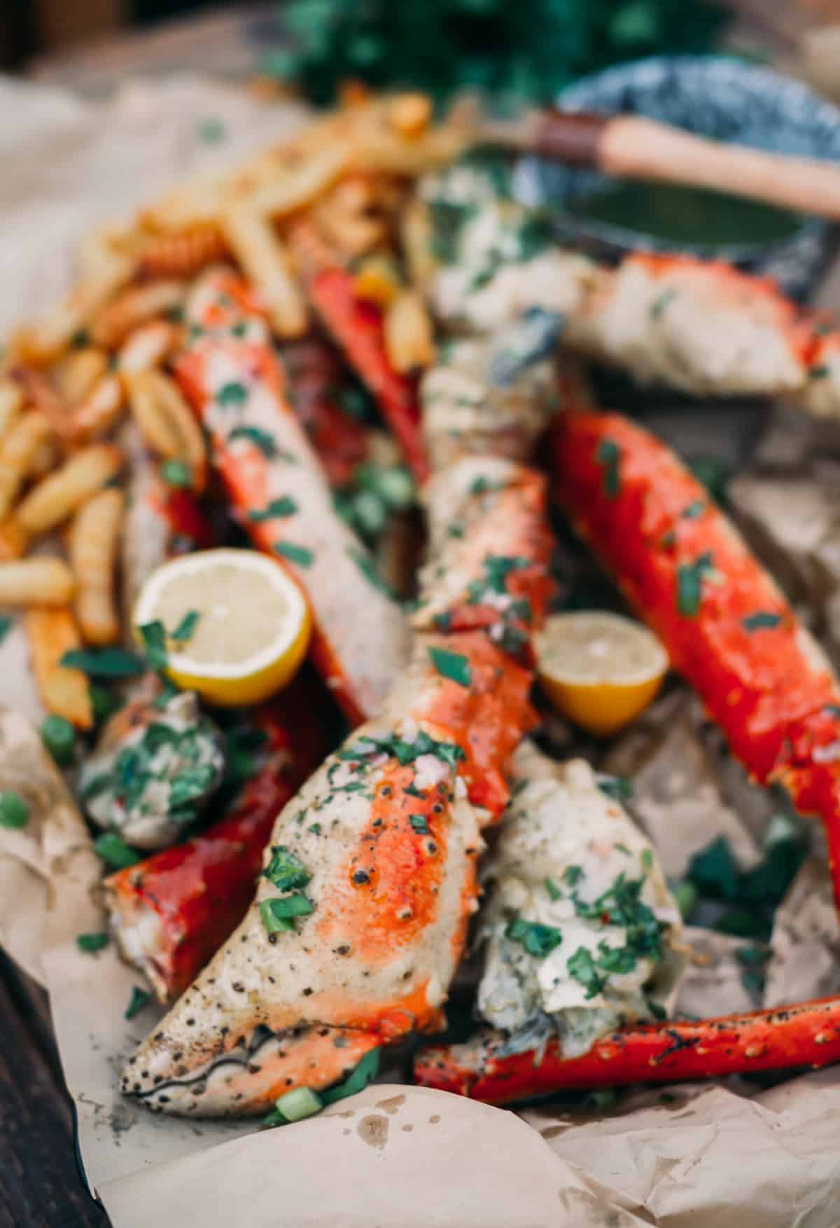 Grilled king crab legs on a paper with lemons and herbs. 