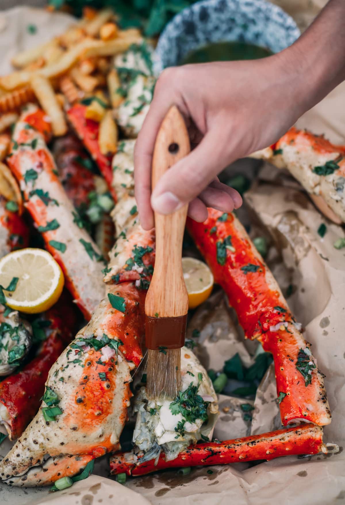Hand basting the crab legs with a brush dipped in chimichurri butter. 