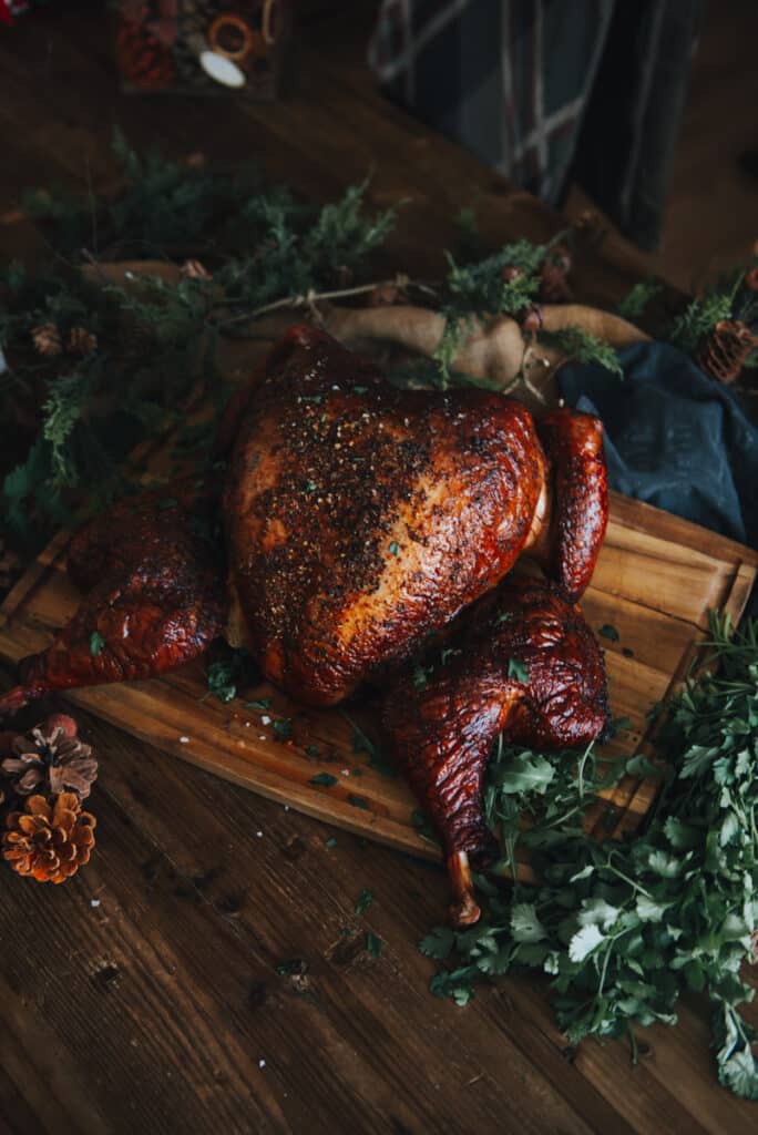 Finished golden brown smoked spatchcocked turkey on a cutting board garnished with salt and parsley. 
