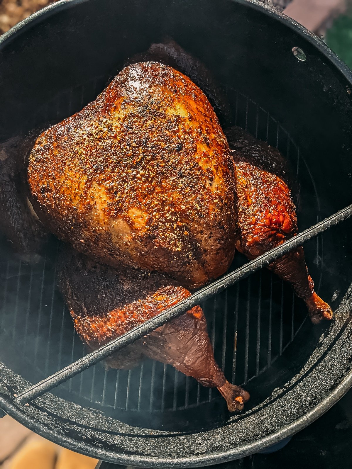Showing the crisp herb rubbed golden brown skin of a turkey on a smoker. 