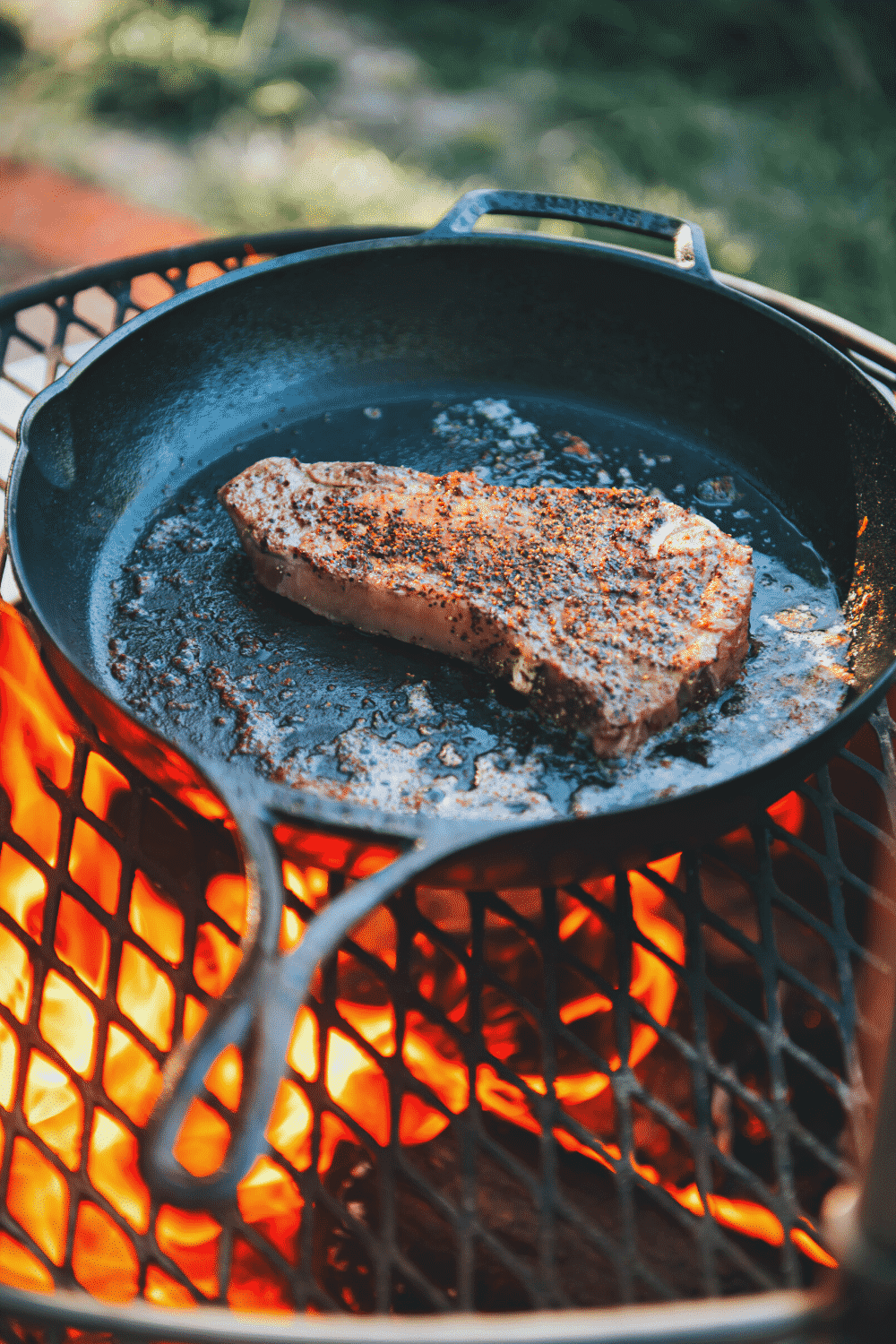 Steak in lodge cast iron over fire.