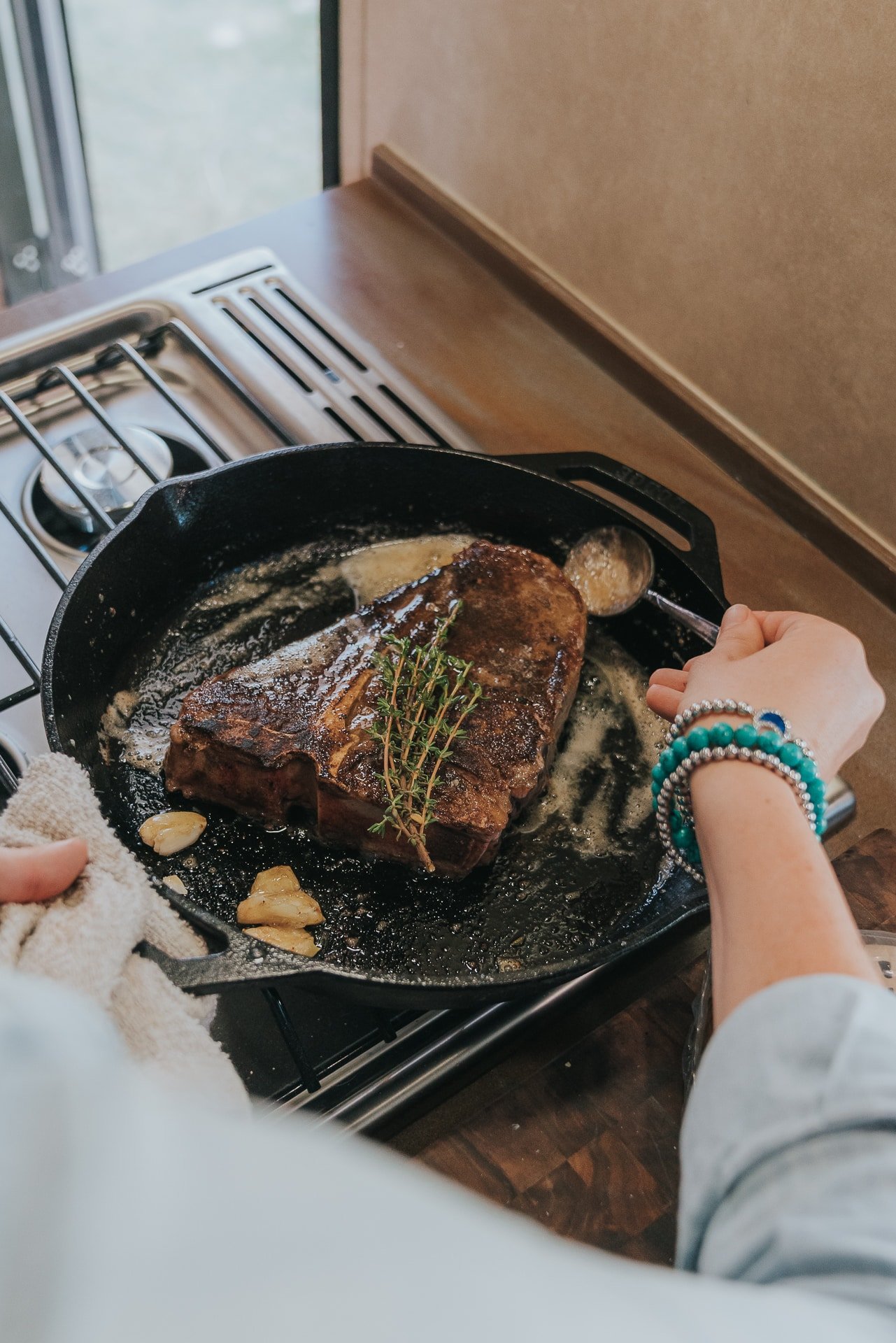 Porterhouse steak in a skillet with garlic and herbs. 