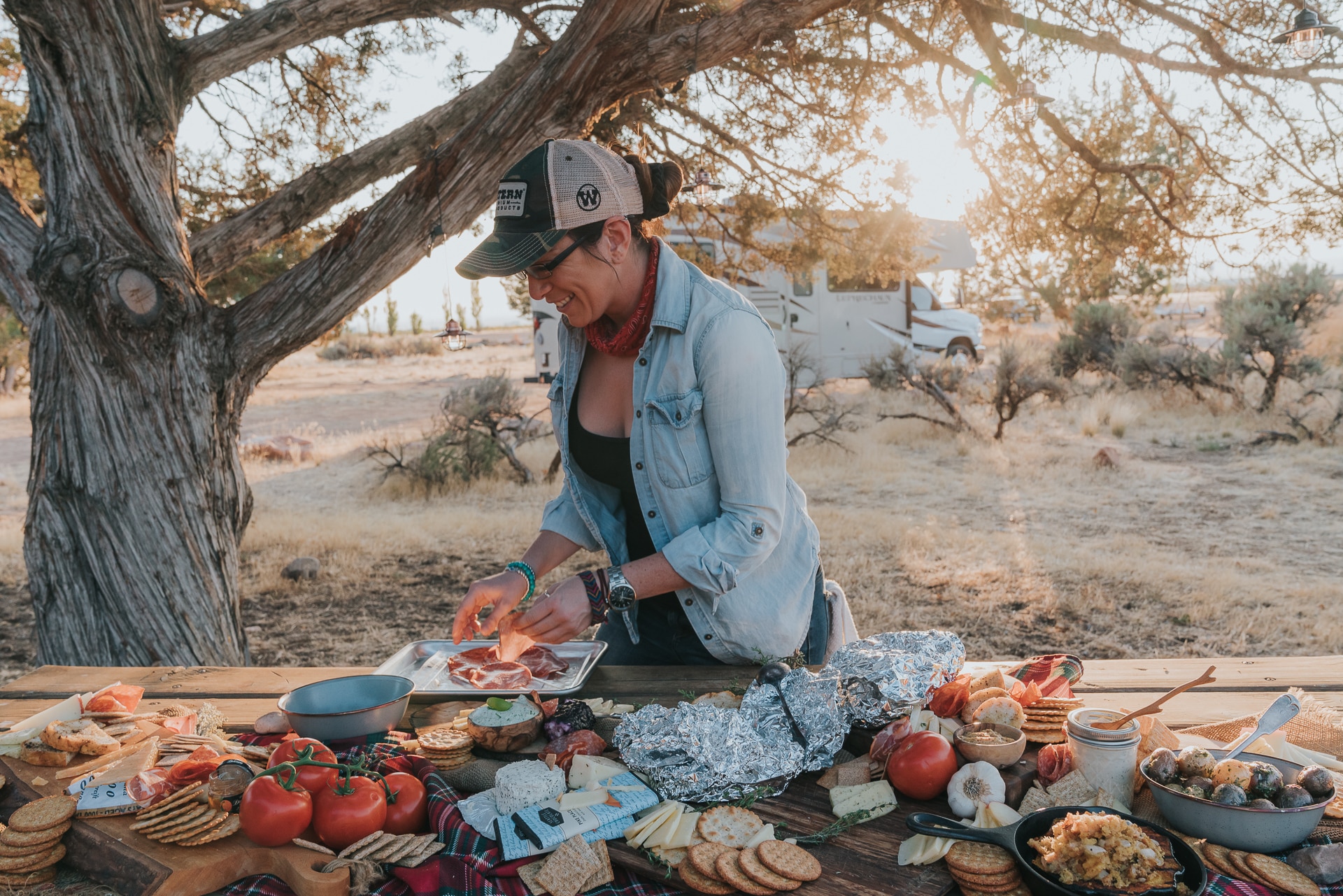 Woman smiling, arranging cured meats on platters. 