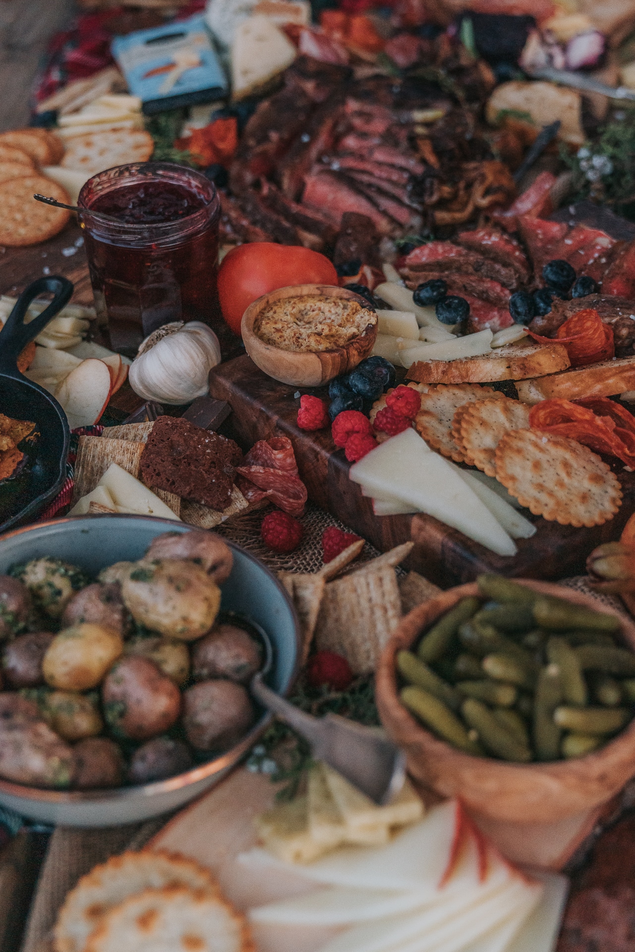 Close up of charcuterie board with layers of different meats and various slices of cheese, veggies and mini pickles. 