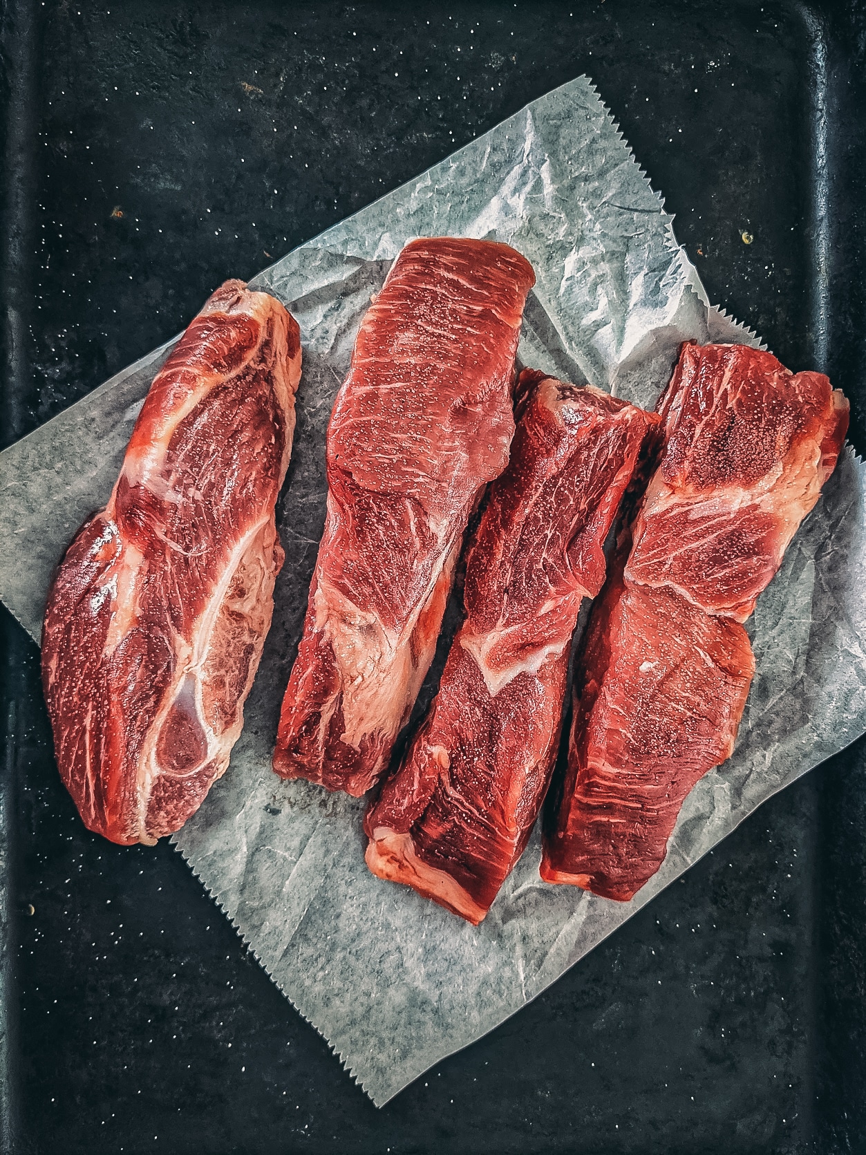 Country style ribs on a black board. 