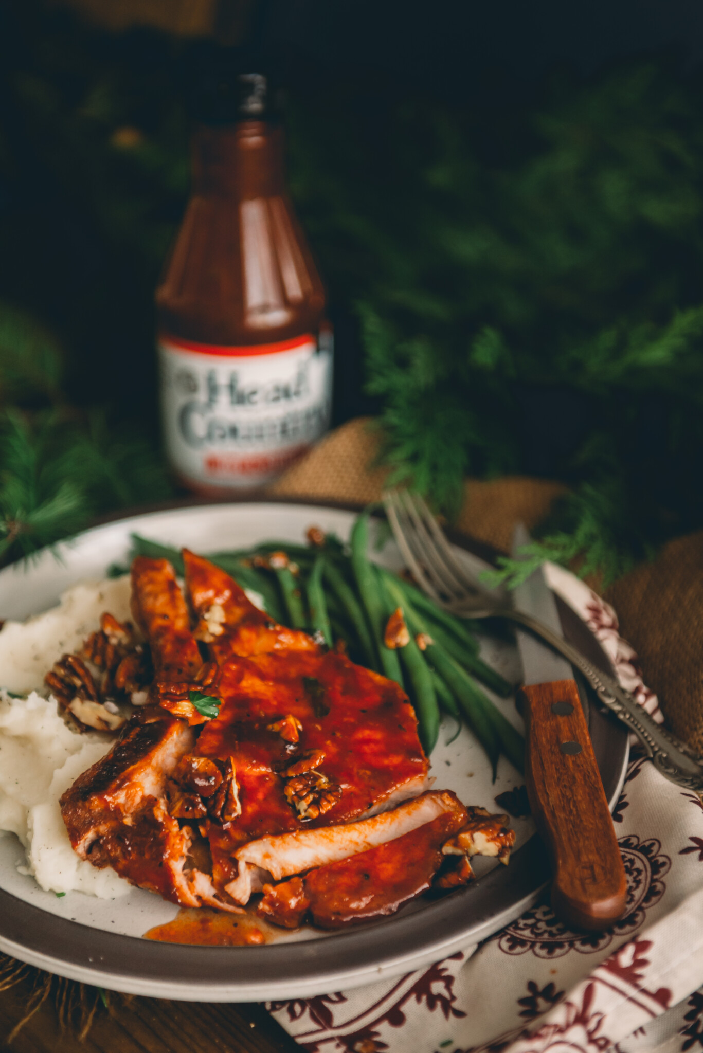 Oven baked bbq pork chops on a plate with green beans and mashed potatoes. 