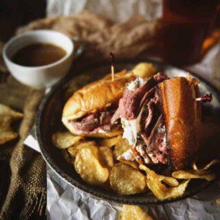 French dip sandwich with au jus and chips.
