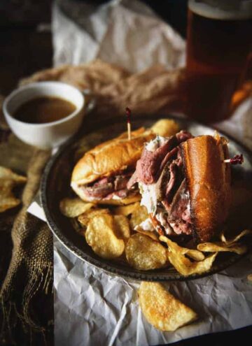 French dip sandwich with au jus and chips.