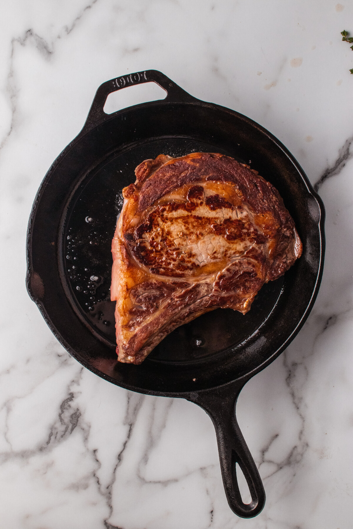Crust on a ribeye steak in a skillet. 