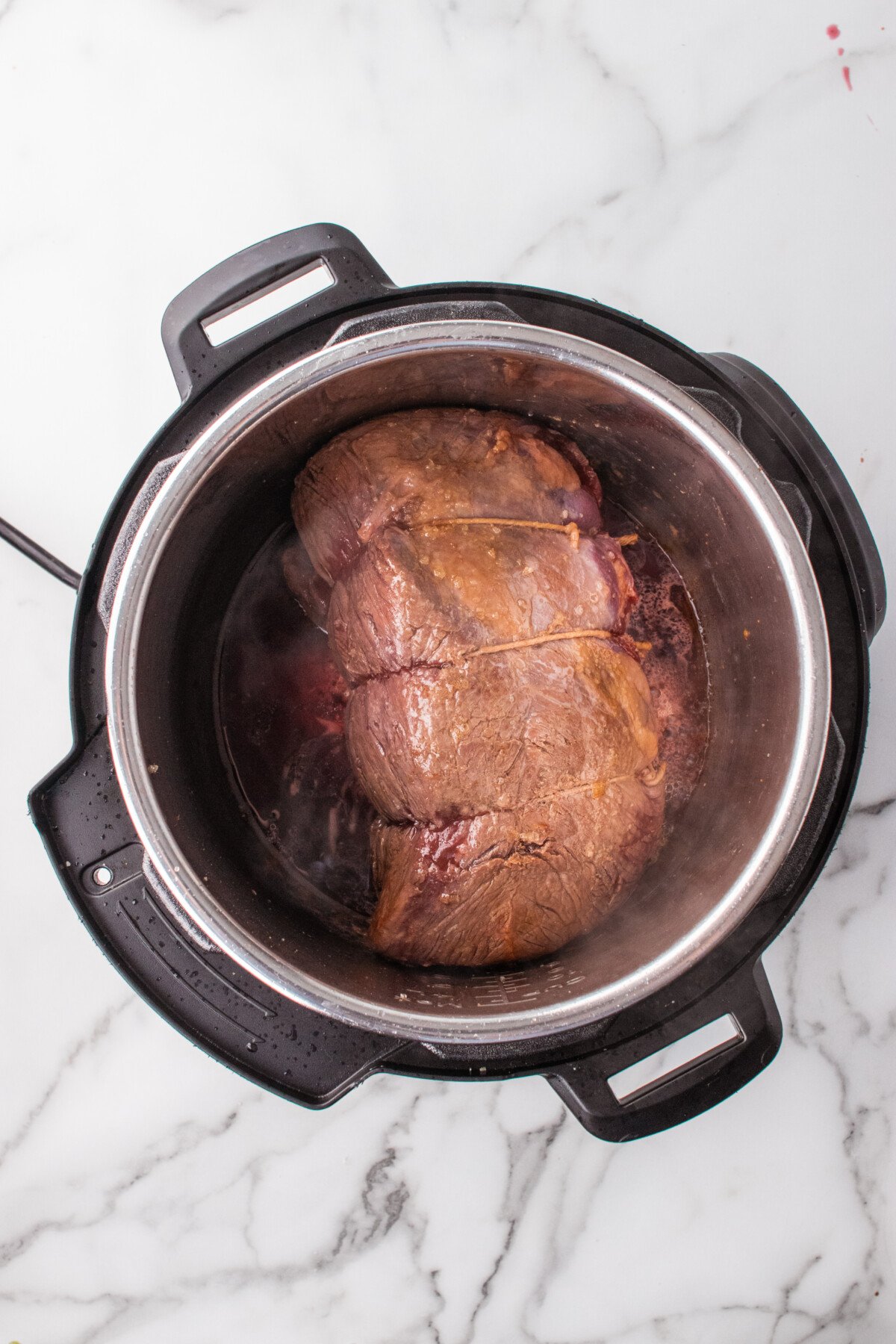 Roast being seared on all sides in the pressure cooker before the other ingredients are added.