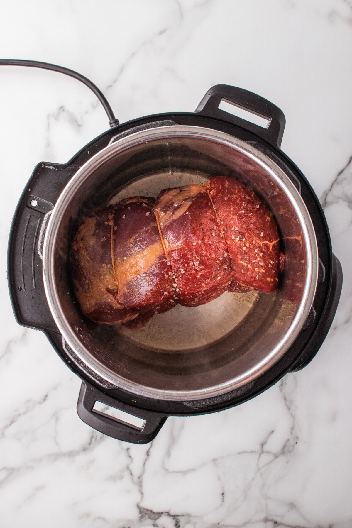 The roast placed in the bottom of an instapot pressure cooker. 