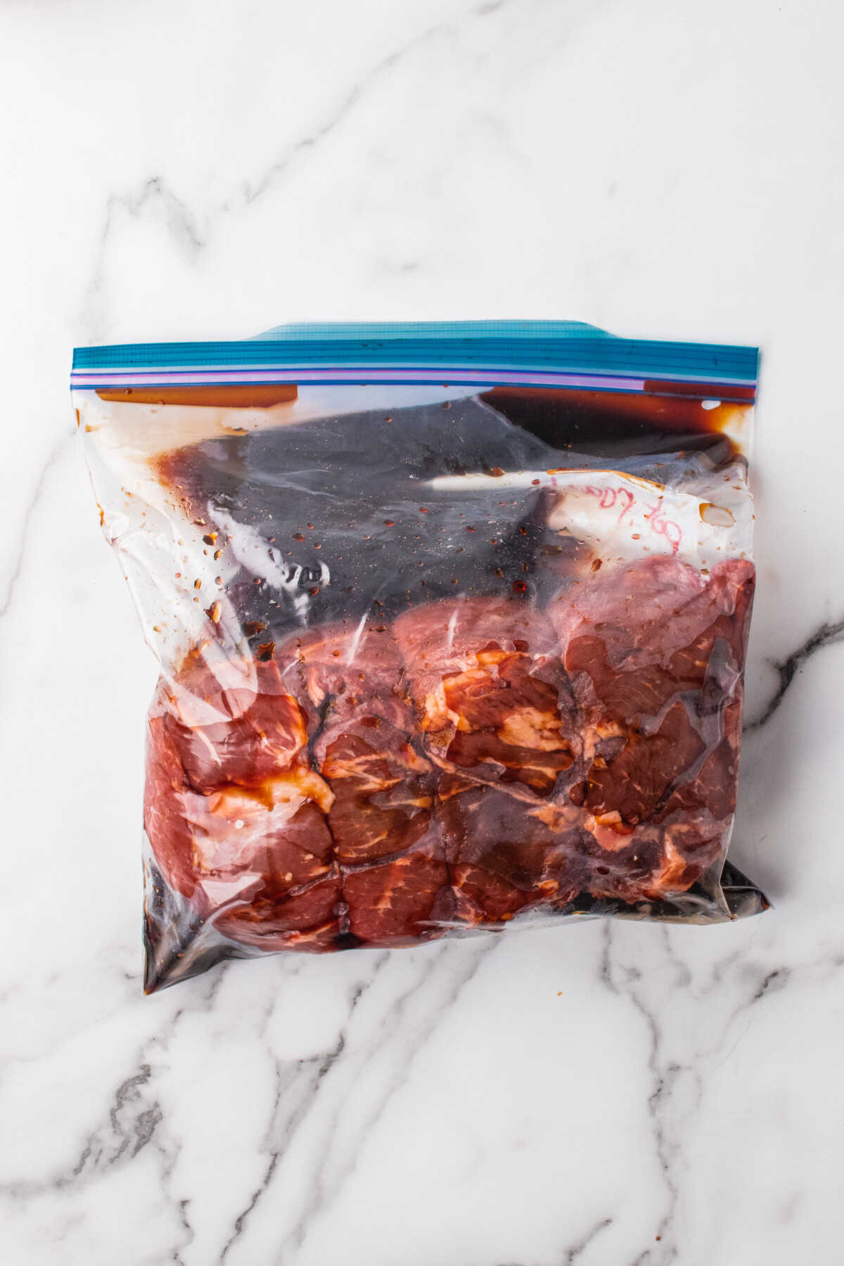 Chuck roast added to a bag with marinade being poured in.