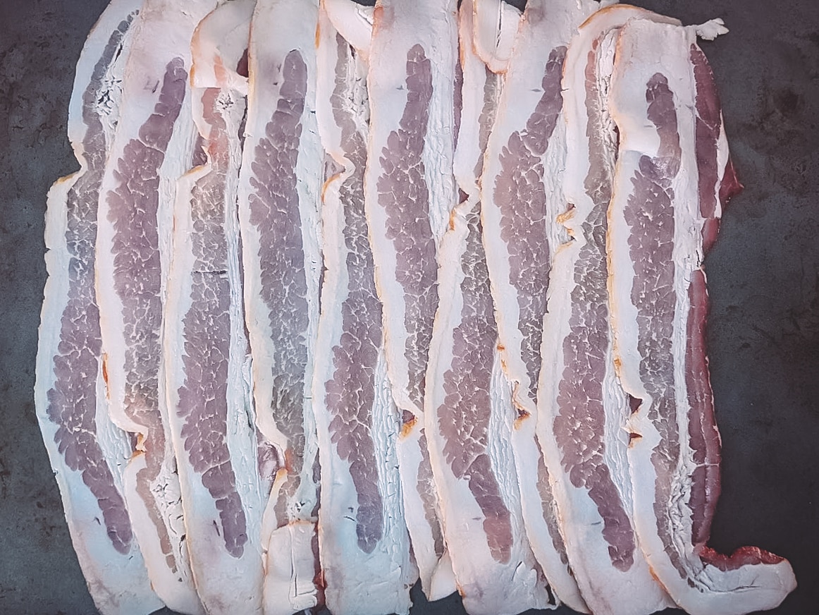 Slices of bacon arranged on a clean work surface. 