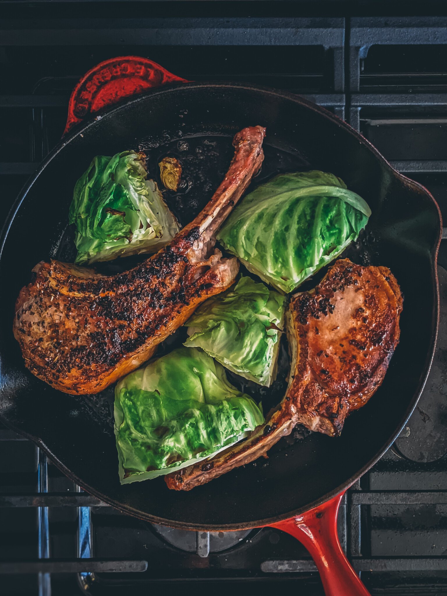 Pork chops in a cast iron pan with cabbage wedges seared to perfection. 