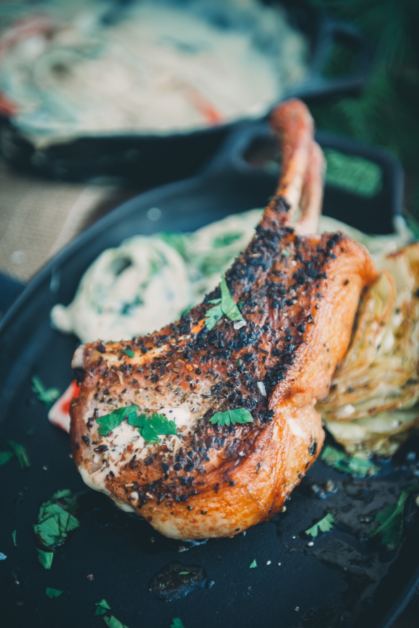 Close up of a pan seared pork chop with a golden brown curst plated and garnished with chopped parsley. 