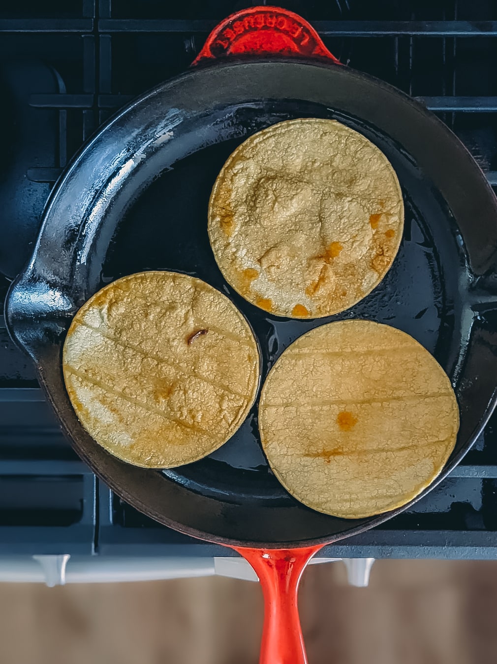Corn tortillas in a frying pan.