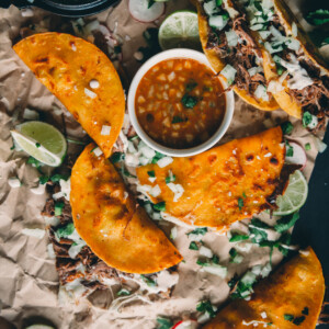 overhead shot of quesabirria tacos on a platter with consume