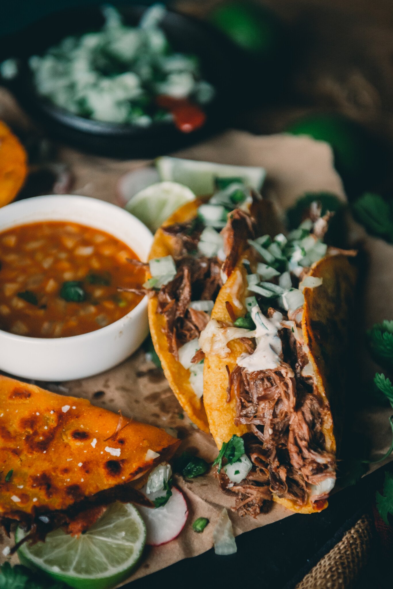 Close up shot of quesabirria tacos showing shredded meat and onion cilantro topping.