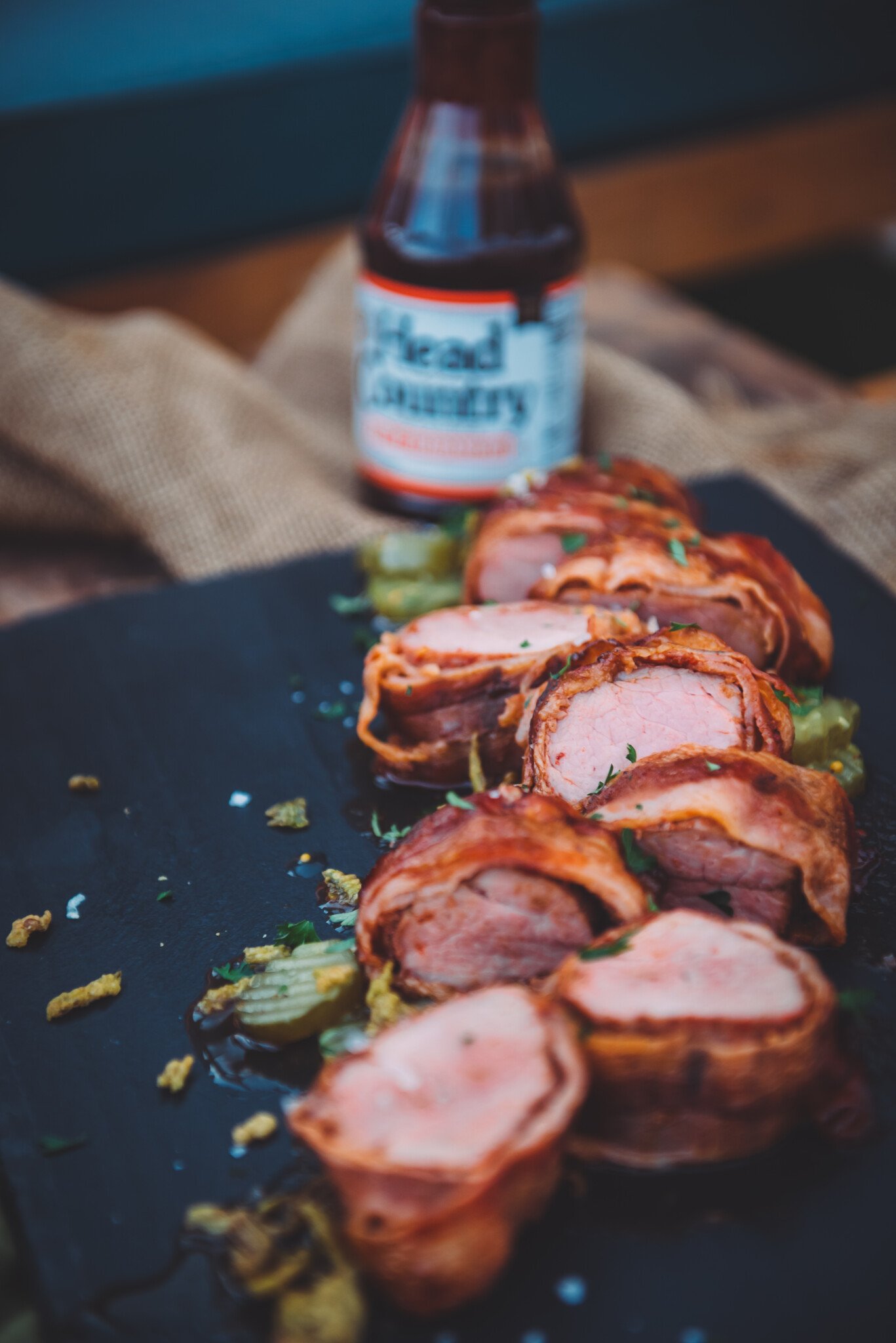 Smoked pork tenderloin sliced and arranged on a board to slow light pink center. 