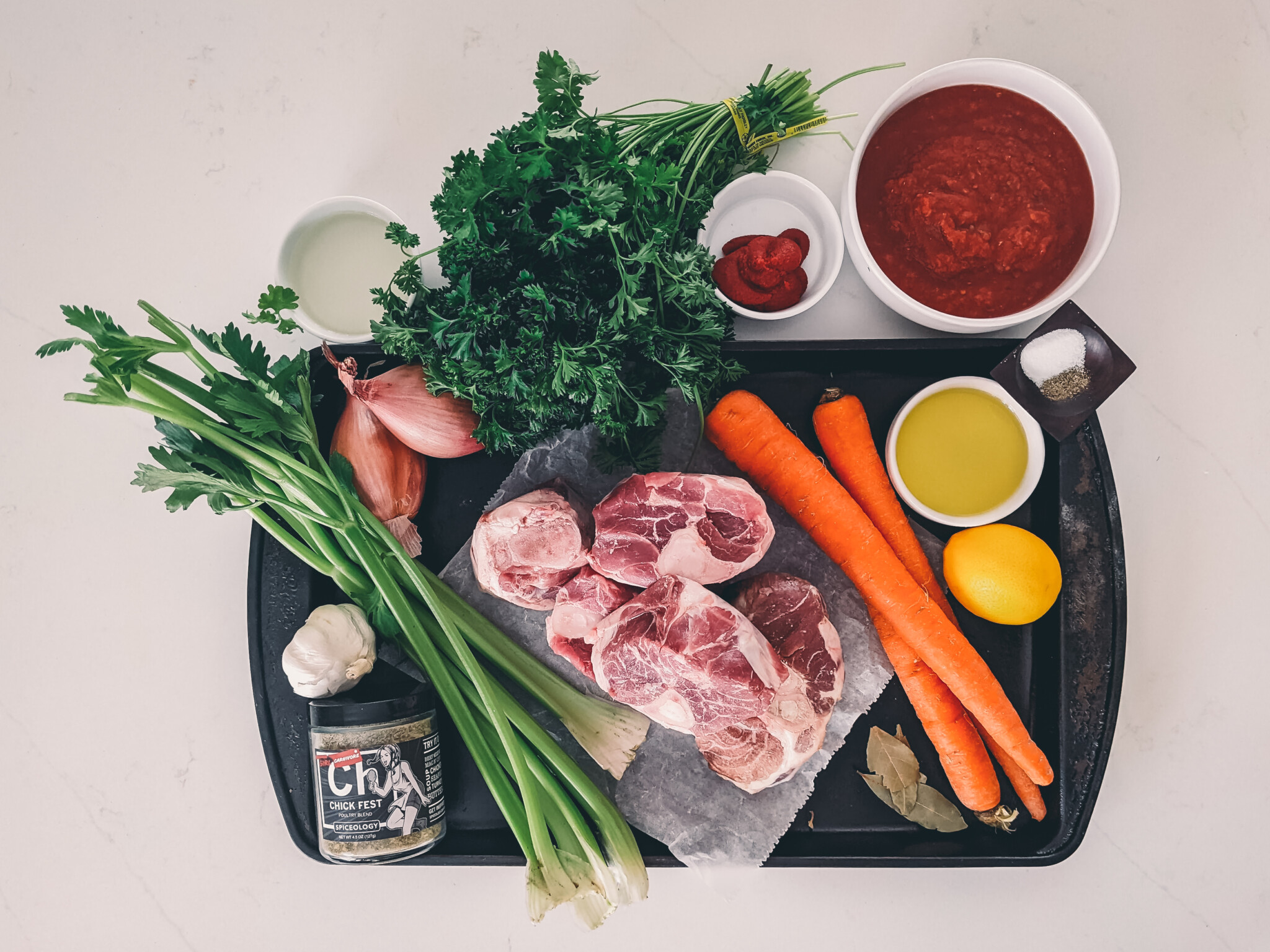 Ingredients needed for sous vide osso buco; pork shanks, carrots, celery, onion, spices, garlic, crushed tomatoes, shallots, wine, parsley, lemon salt and pepper