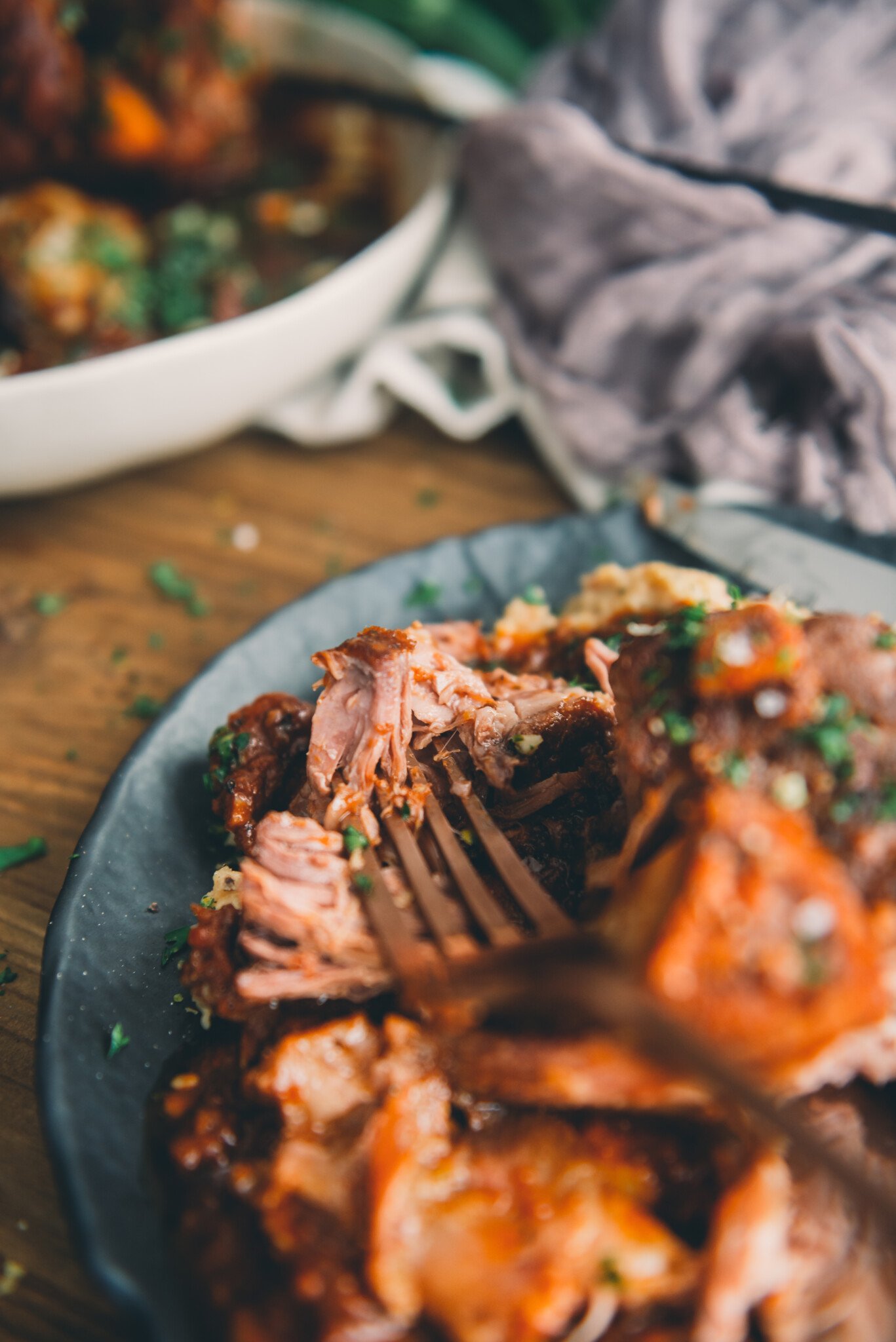 Close up of pork osso buco falling off the bone with a fork 