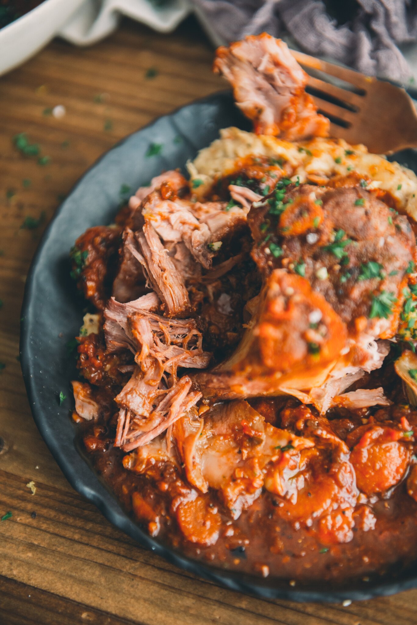 Close up showing tender bites of pork shank easily removed from the bone due to the perfect cook from sous vide.