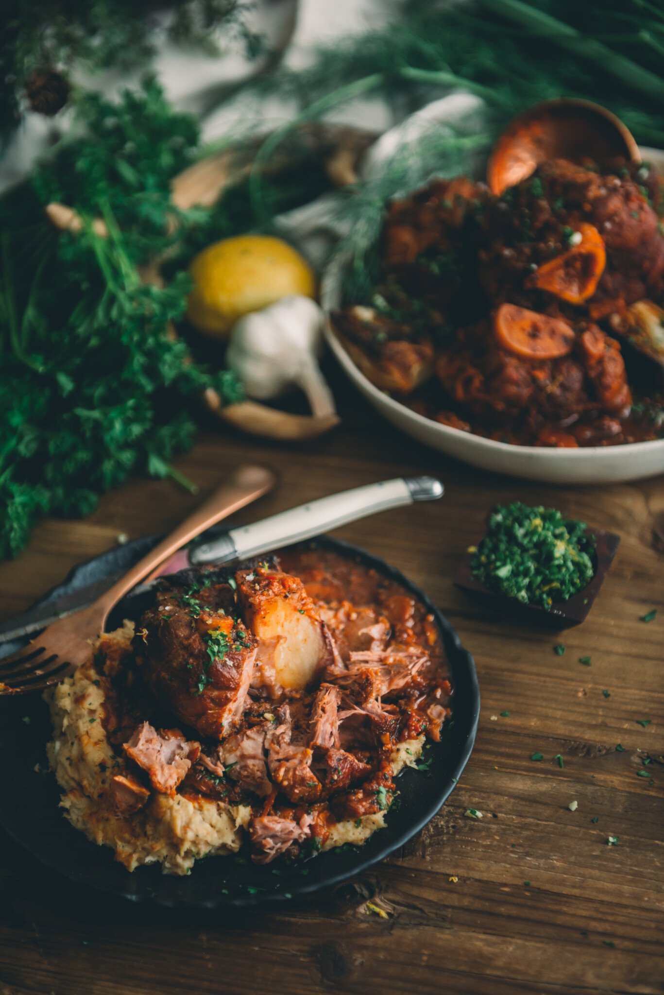 Platter of tender pork over mashed root veggies on a rustic table. 