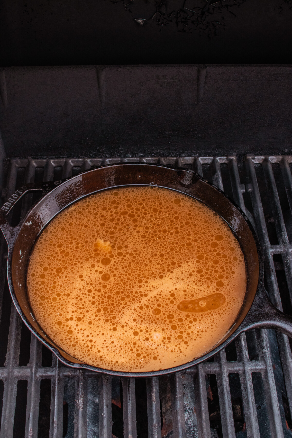 Liquid bubbling in cast iron skillet on grill.