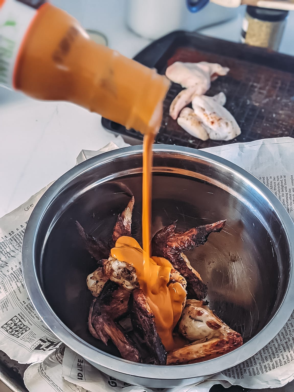 buffalo sauce being poured over air fried chicken wings 